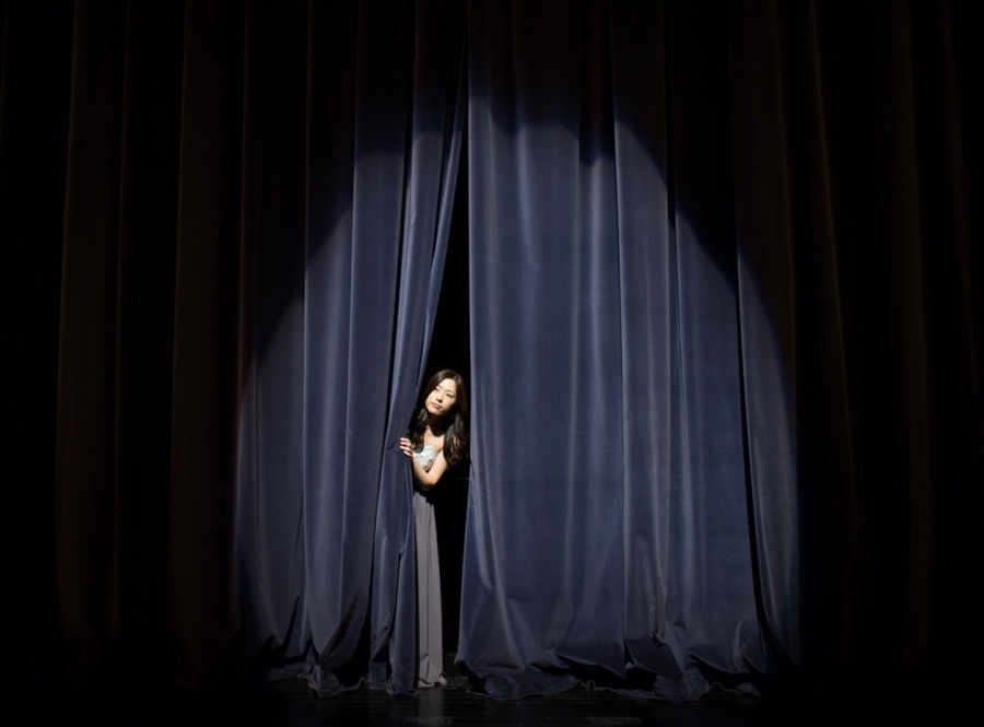 person peeking around a curtain with a spotlight